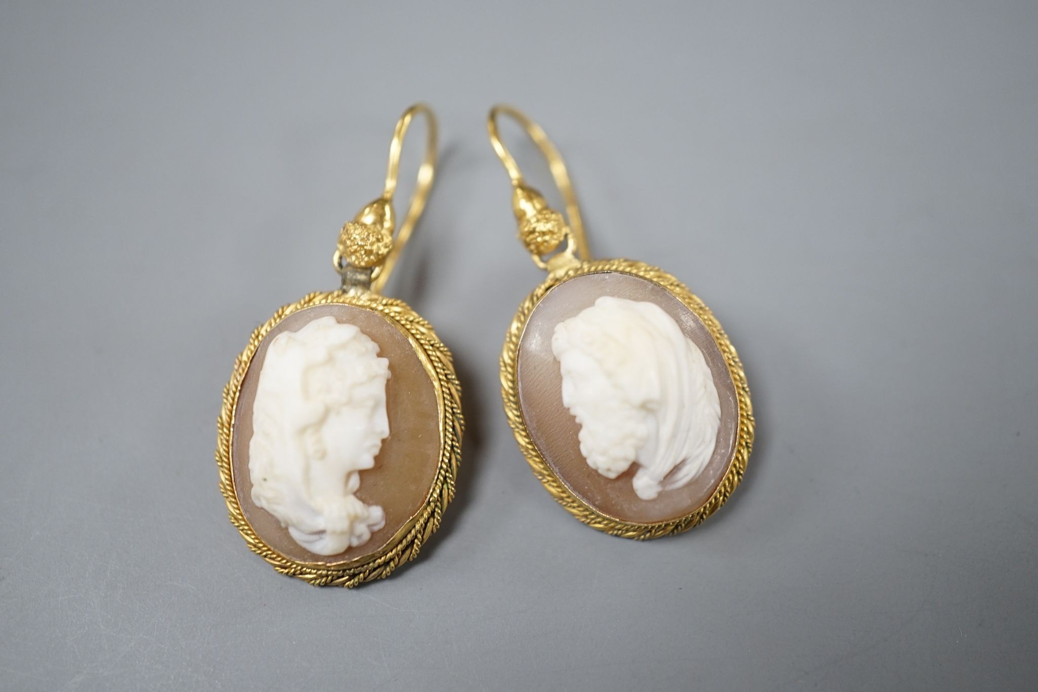 A pair of early 20th century yellow metal and oval cameo shell earrings, carved with a lady to sinister and a gentleman to dexter, overall 40mm, gross 6.2 grams.